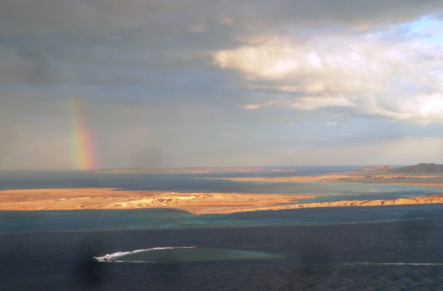 Rainbow with a circular coral reef visible in the foreground